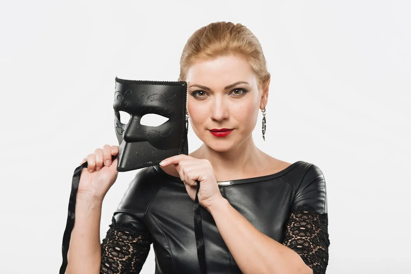 Eine Frau hält eine schwarze Maske in den Händen.
